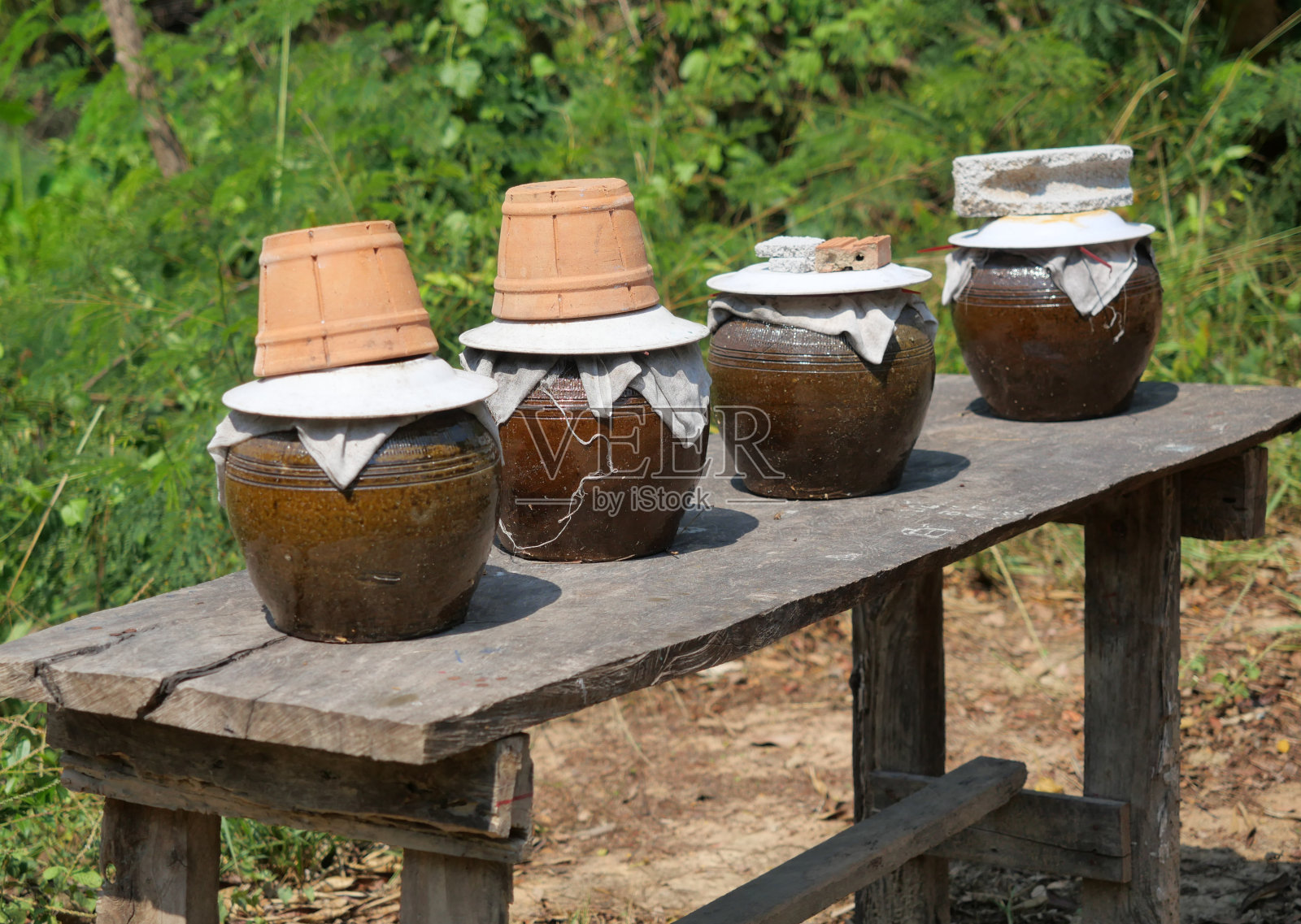 木桌上放着四个陶坛子，里面盛着鱼露照片摄影图片