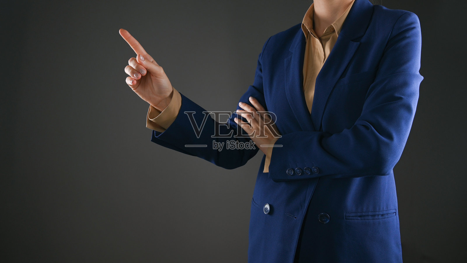 穿夹克的女人用手指着她头顶上的复印区。年轻女子用手指着工作室空白墙上的东西照片摄影图片