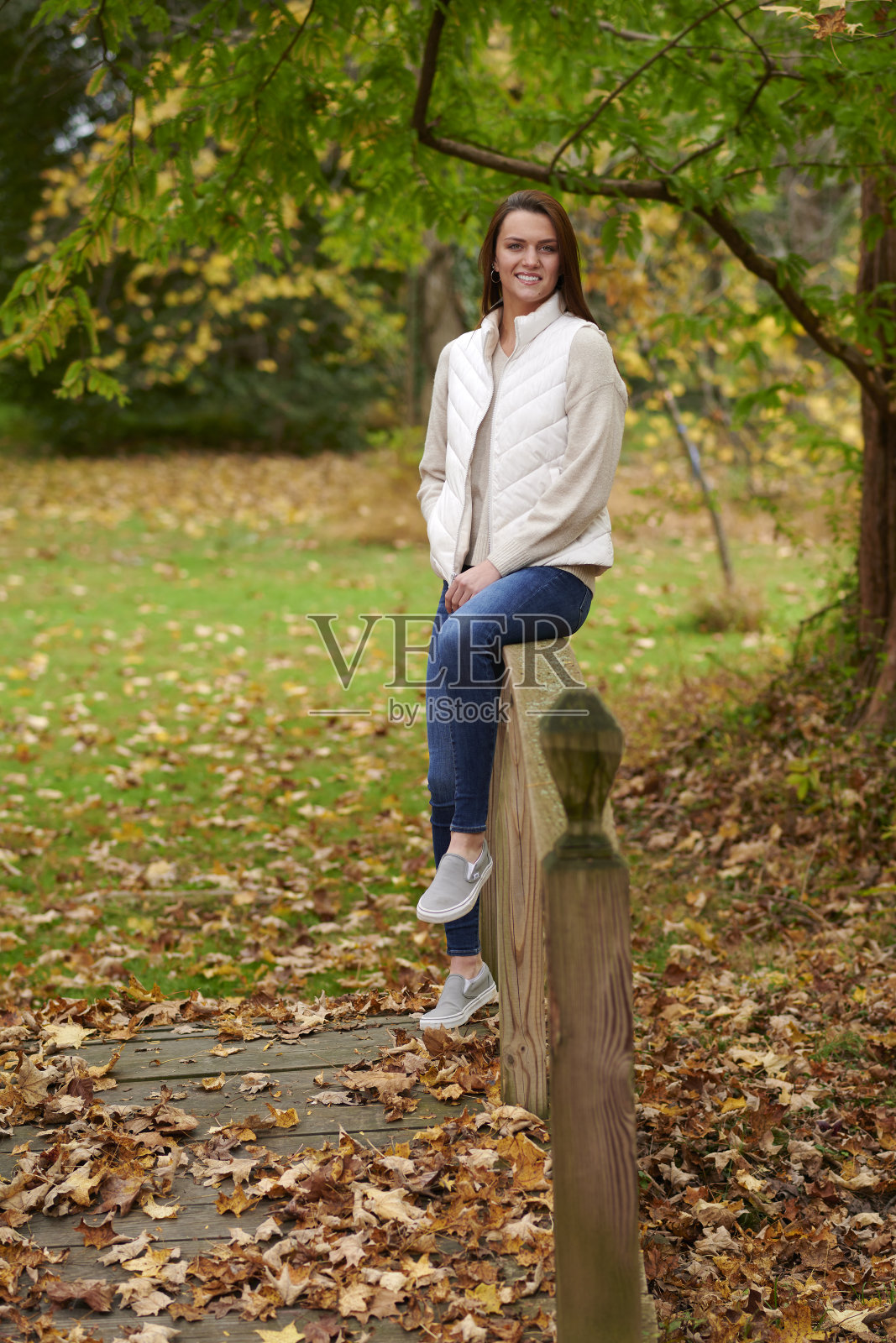 校园里秋叶丛中可爱的年轻女子照片摄影图片