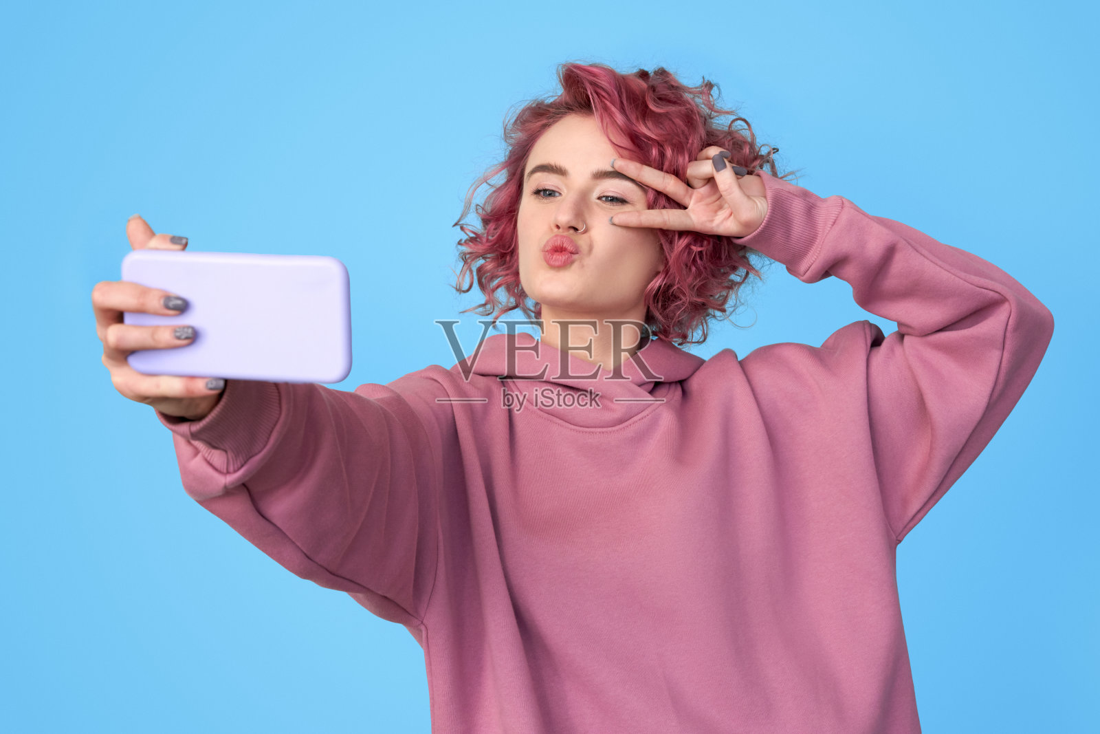 粉色头发的女孩在智能手机上摆姿势自拍照片摄影图片