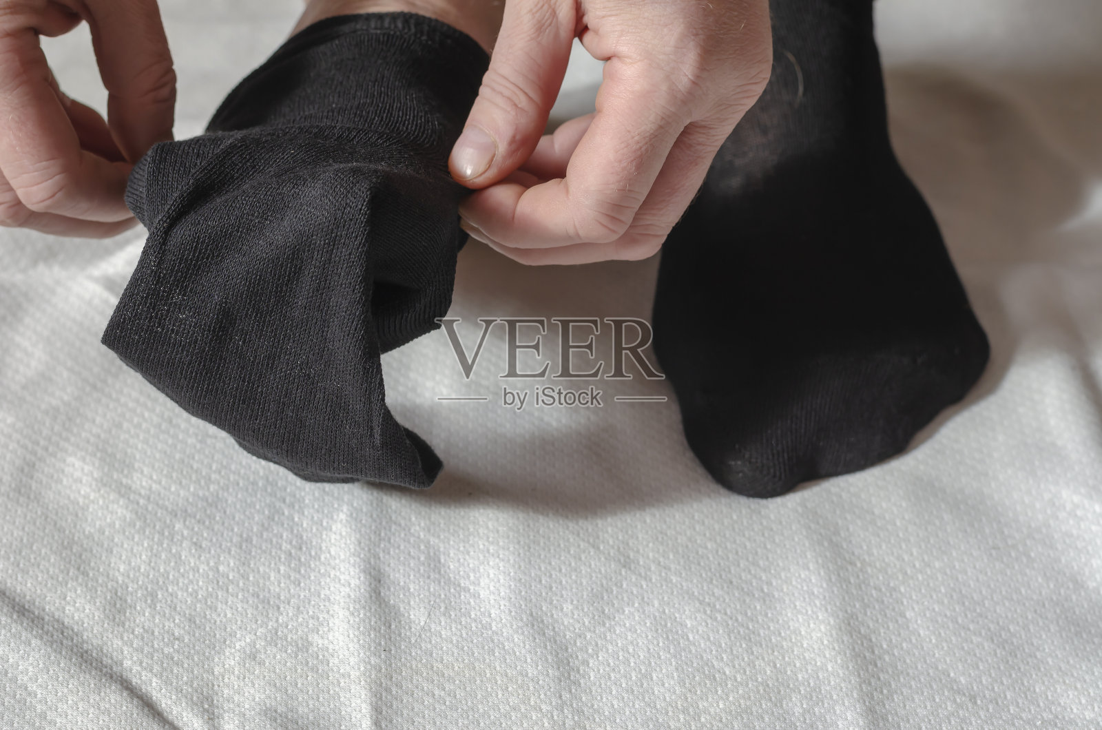 一个成年男子的手穿上了新袜子。照片摄影图片