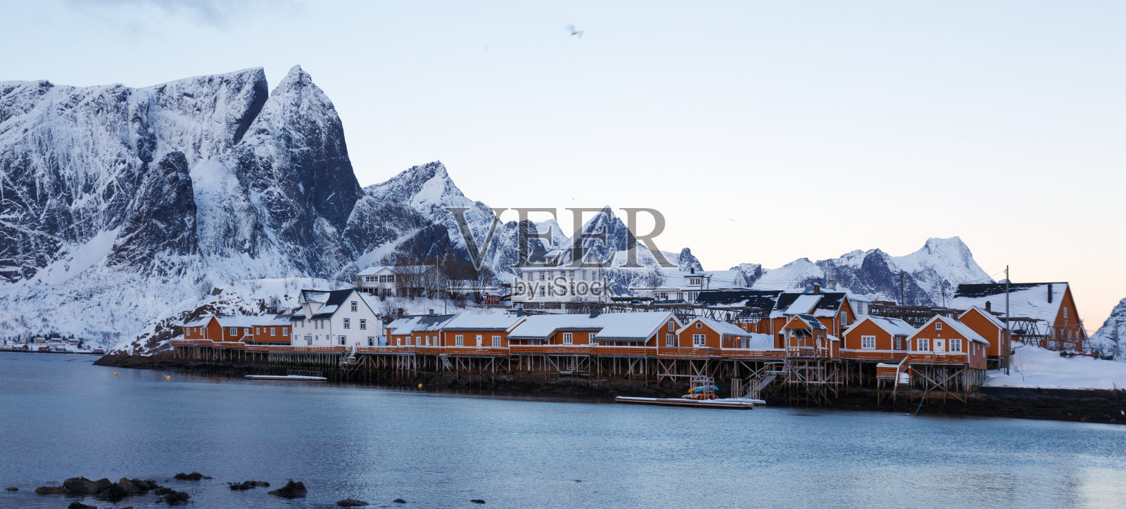 传统的挪威木屋矗立在峡湾岸边和远处的群山中。罗弗敦群岛。挪威。照片摄影图片