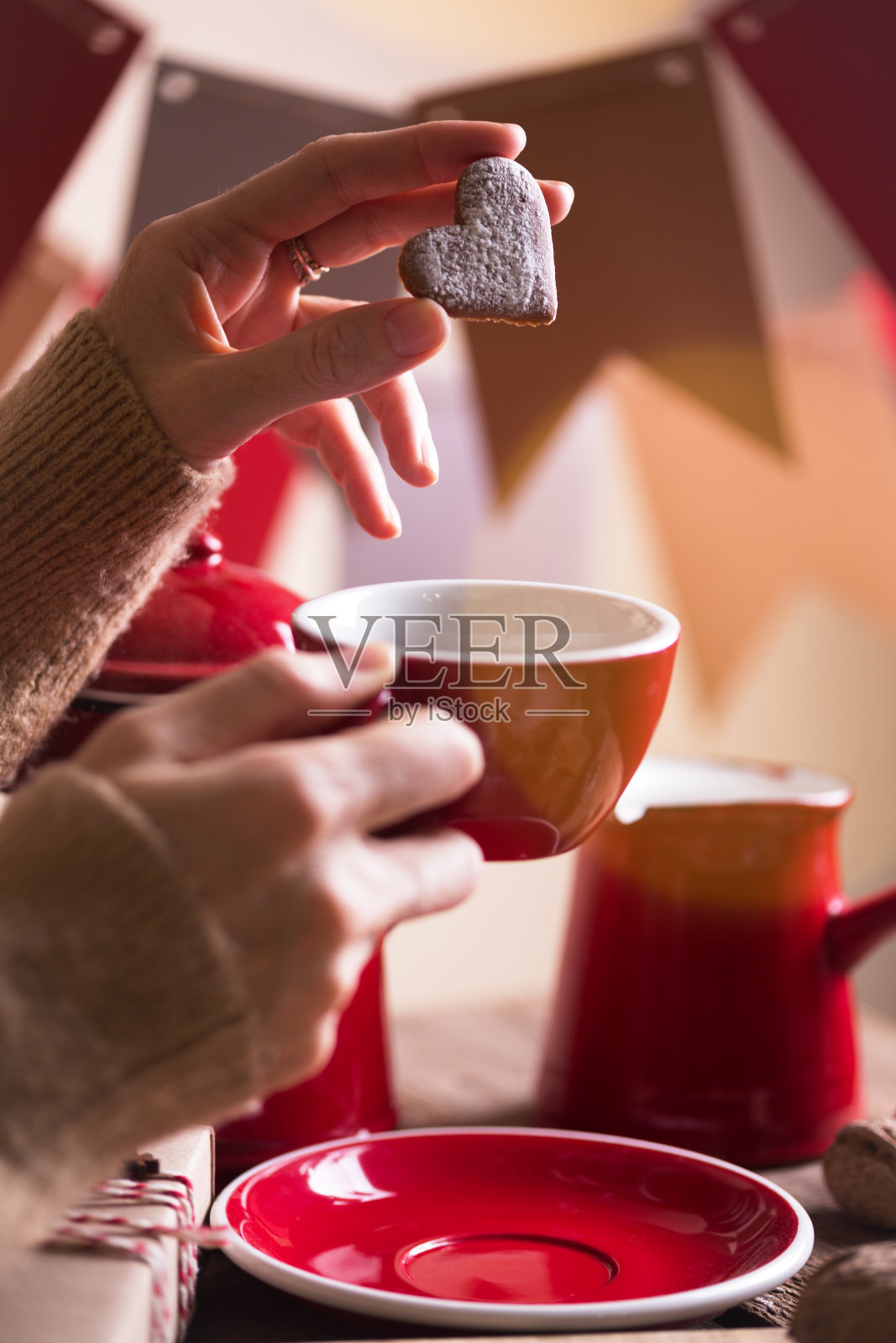 圣诞节的静物画。女孩拿着一个杯子和姜饼在她的手在一个花环的背景旗帜照片摄影图片
