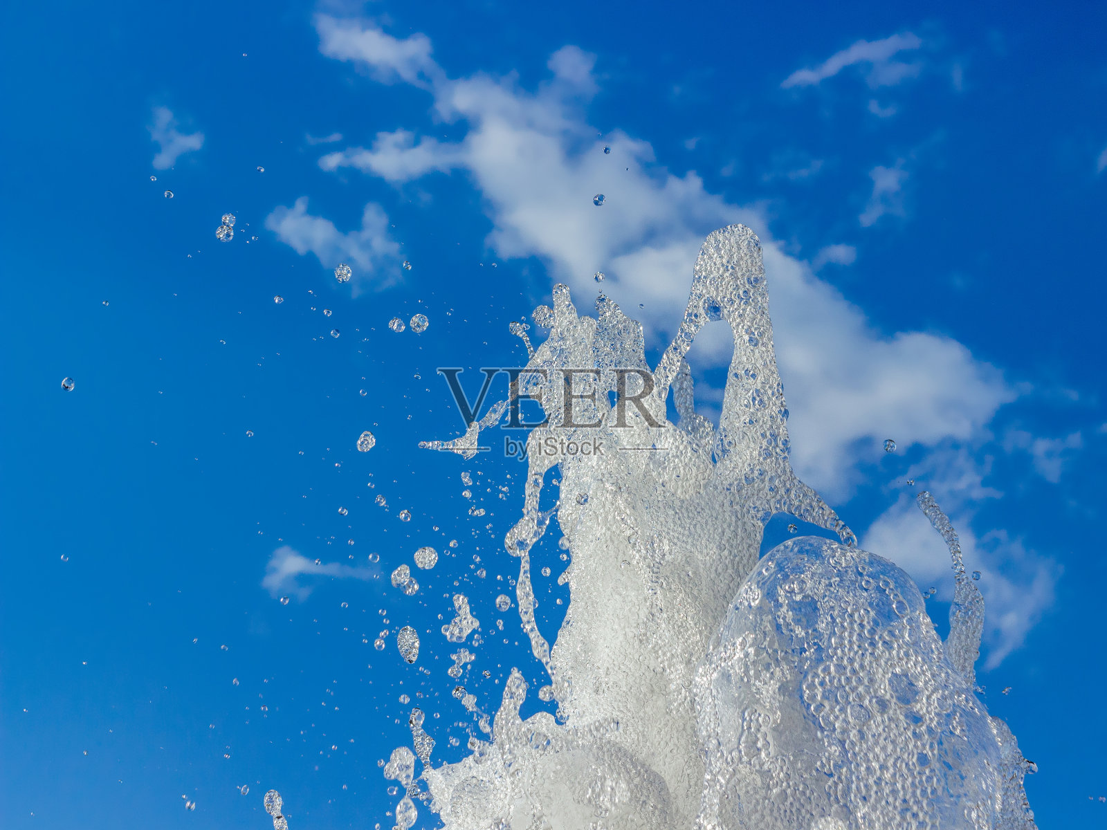 蓝色的天空中喷溅着水珠。照片摄影图片