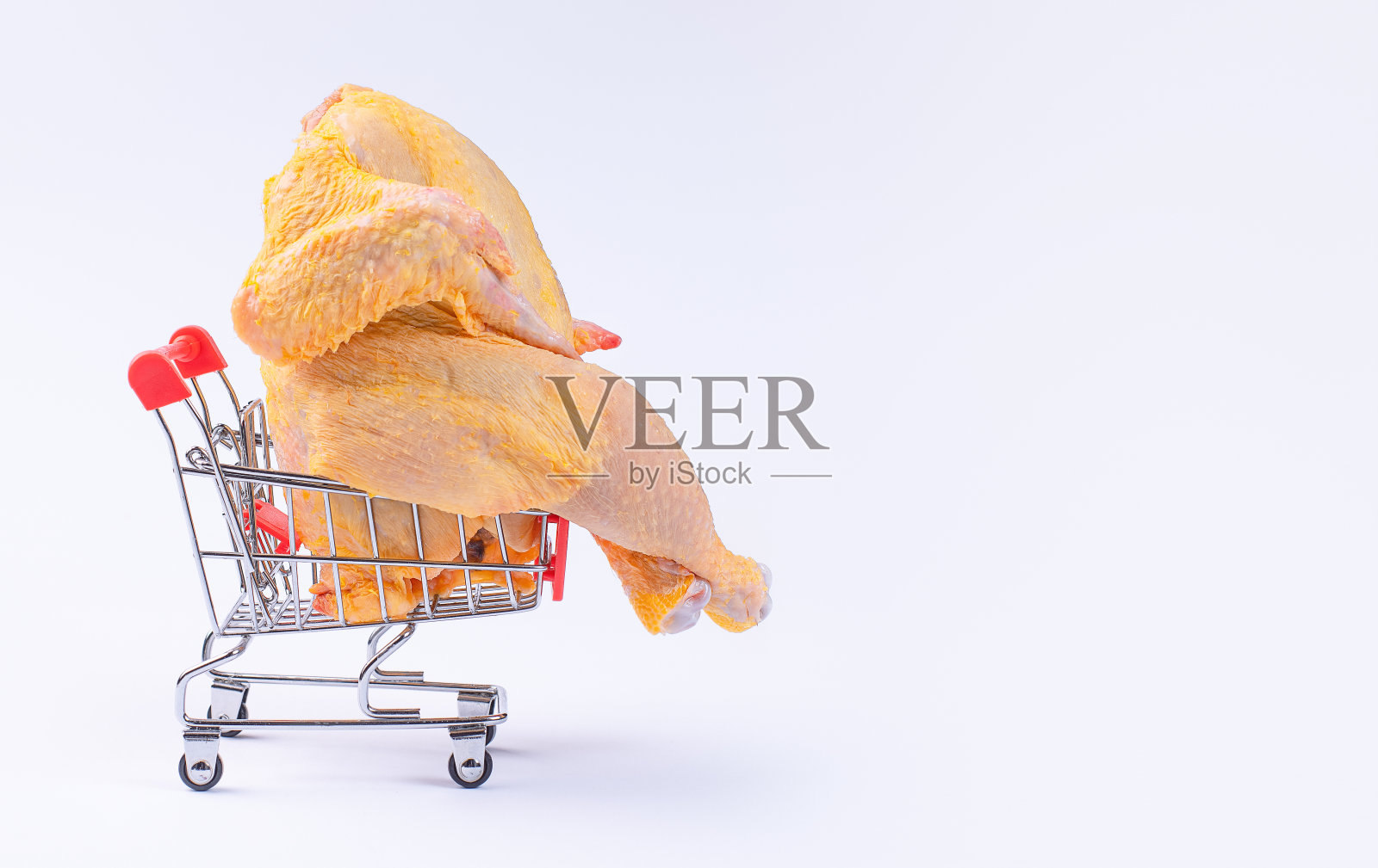 整只鸡放在白色超市的购物车里，减肥食品，白肉鸡，放养。篮子里的新鲜生鸡肉。照片摄影图片