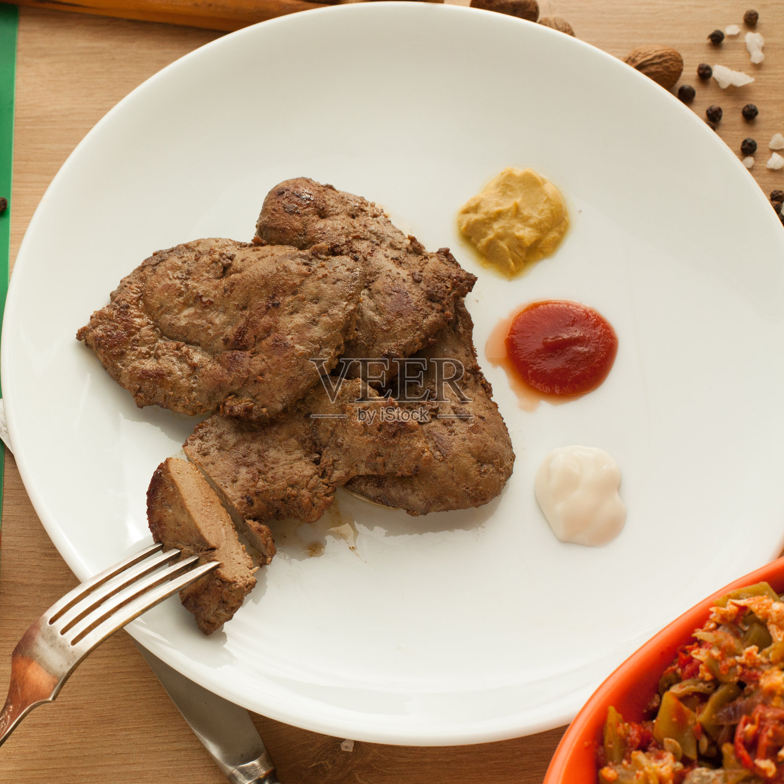 烤肉配番茄酱，蛋黄酱，芥末，肉片挂在叉子上。照片摄影图片