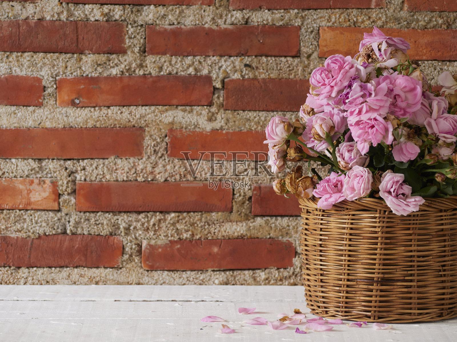 白色木桌上，篮子里的粉红玫瑰照片摄影图片