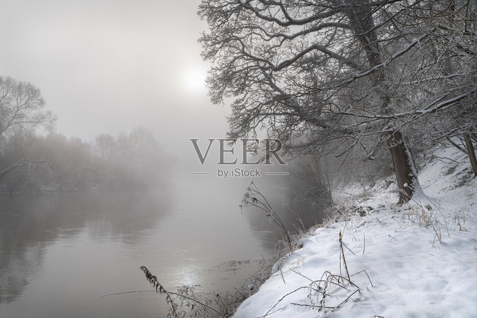 苏格兰边境冬雪中，阳光透过Teviot河上的薄雾照片摄影图片