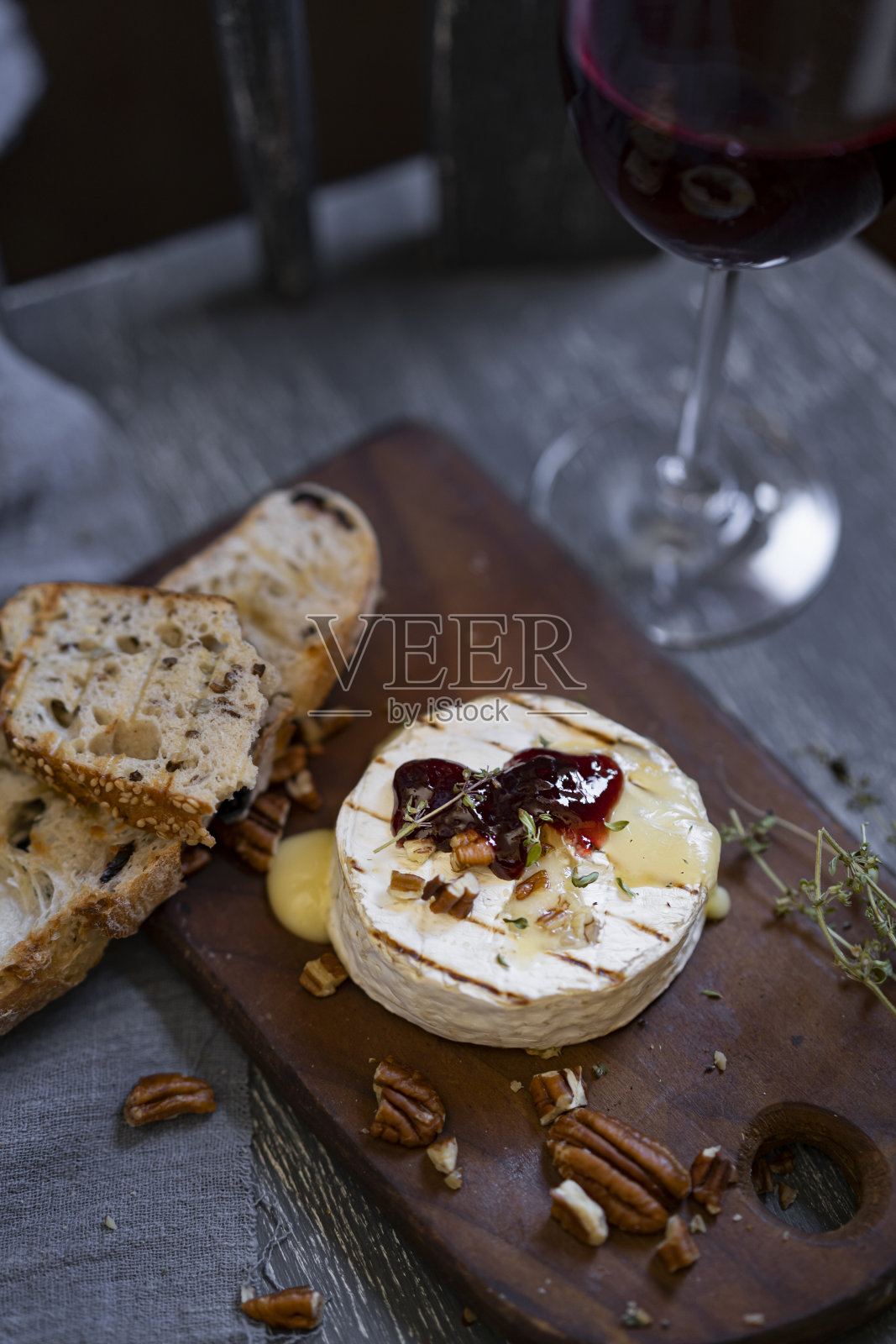 烤卡芒贝尔奶酪或布里干酪配面包、坚果、香草和果酱照片摄影图片