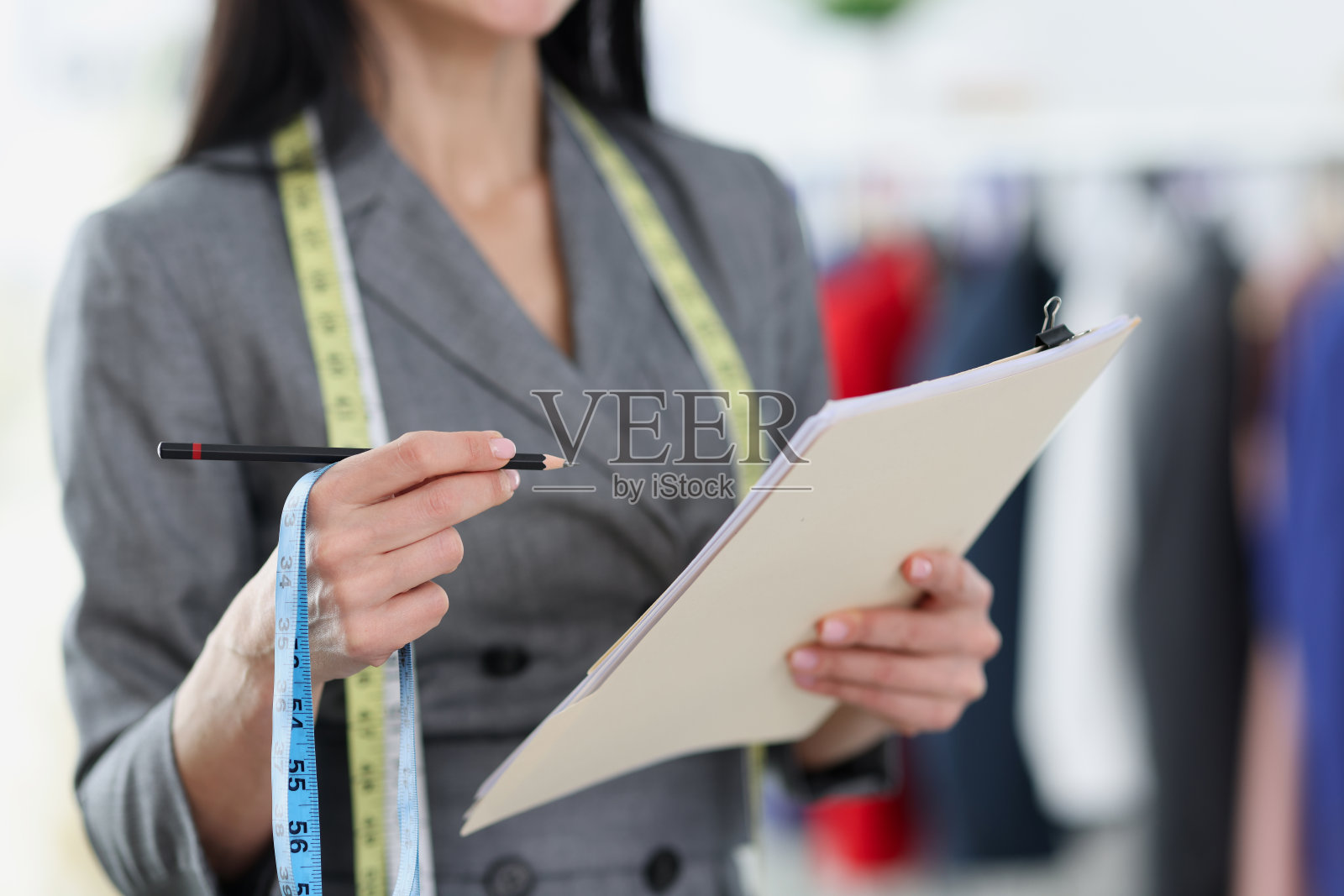 女裁缝用铅笔在纸上写下尺寸的特写照片摄影图片