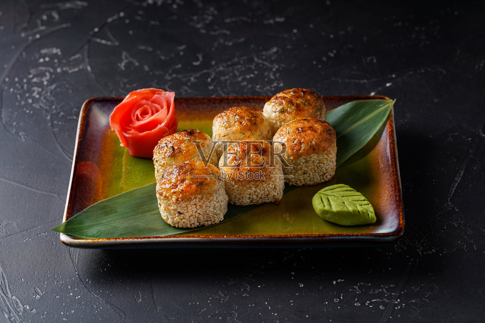 一套烤芝麻寿司卷与芥末和生姜在黑色的背景。日本东方美食。在板上。照片摄影图片