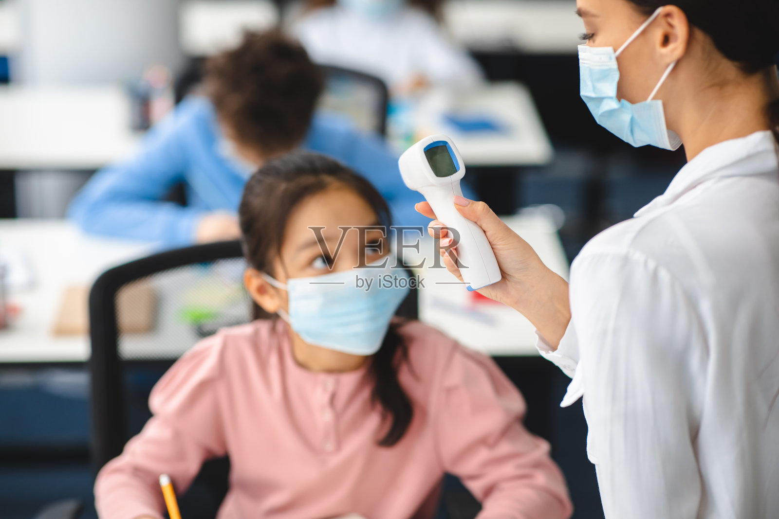 教师用非接触式温度计测量亚洲女孩的温度照片摄影图片