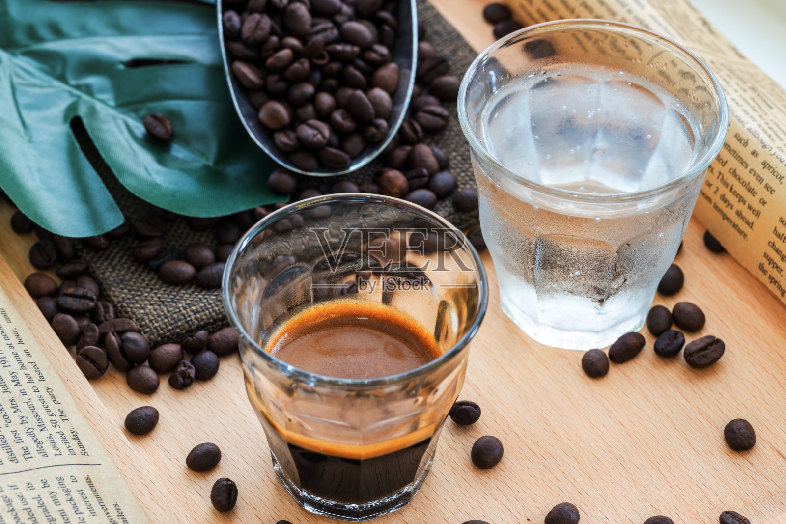 浓缩咖啡在咖啡豆堆旁边的玻璃地方。国际知名芳香饮料。旧木桌上放着一杯咖啡。照片摄影图片