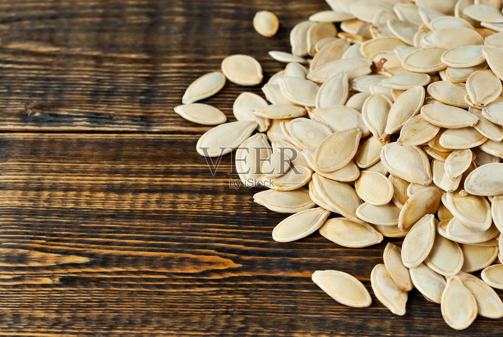 在棕色刮板上的南瓜子。旧木头桌子上坚果的纹理。很多坚果堆在一起。放置文本和复制空间附近的种子。照片摄影图片