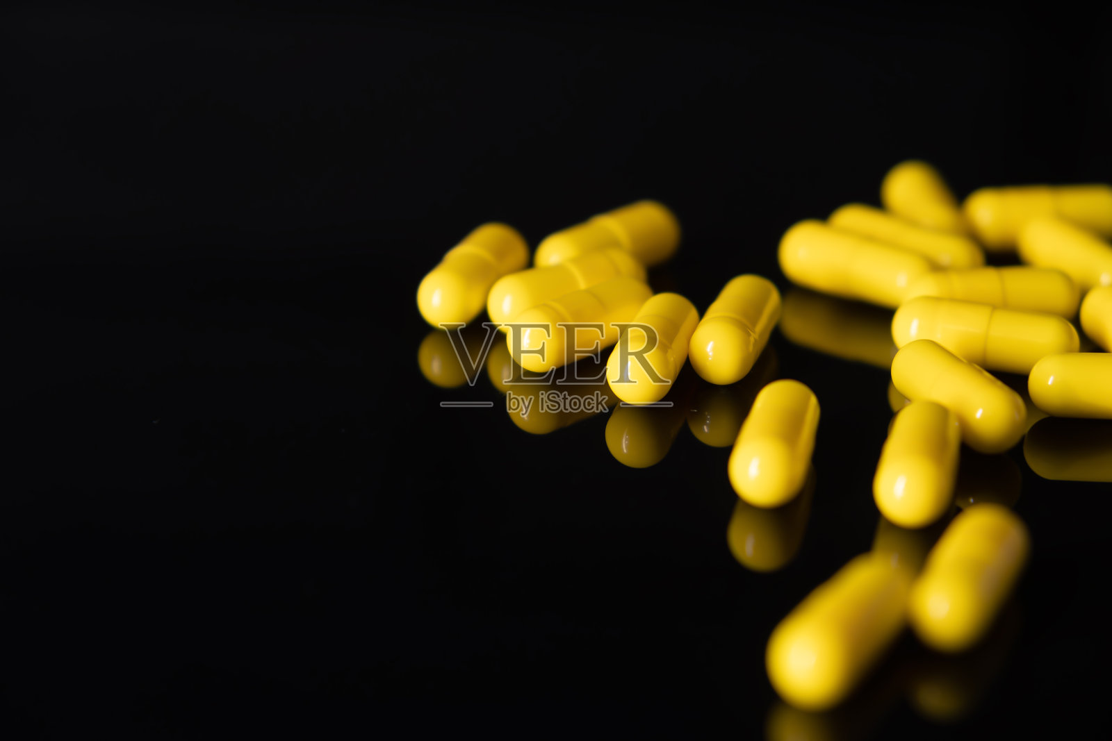 黄色药用胶囊，黑色背景照片摄影图片