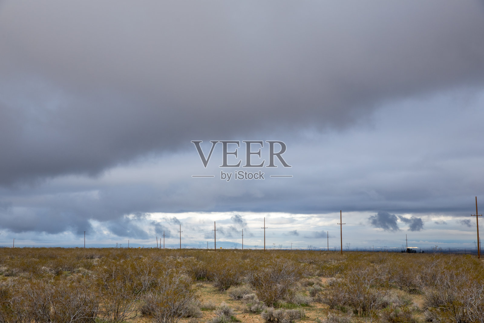 空旷的沙漠景观，乌云密布的天空和电线杆照片摄影图片
