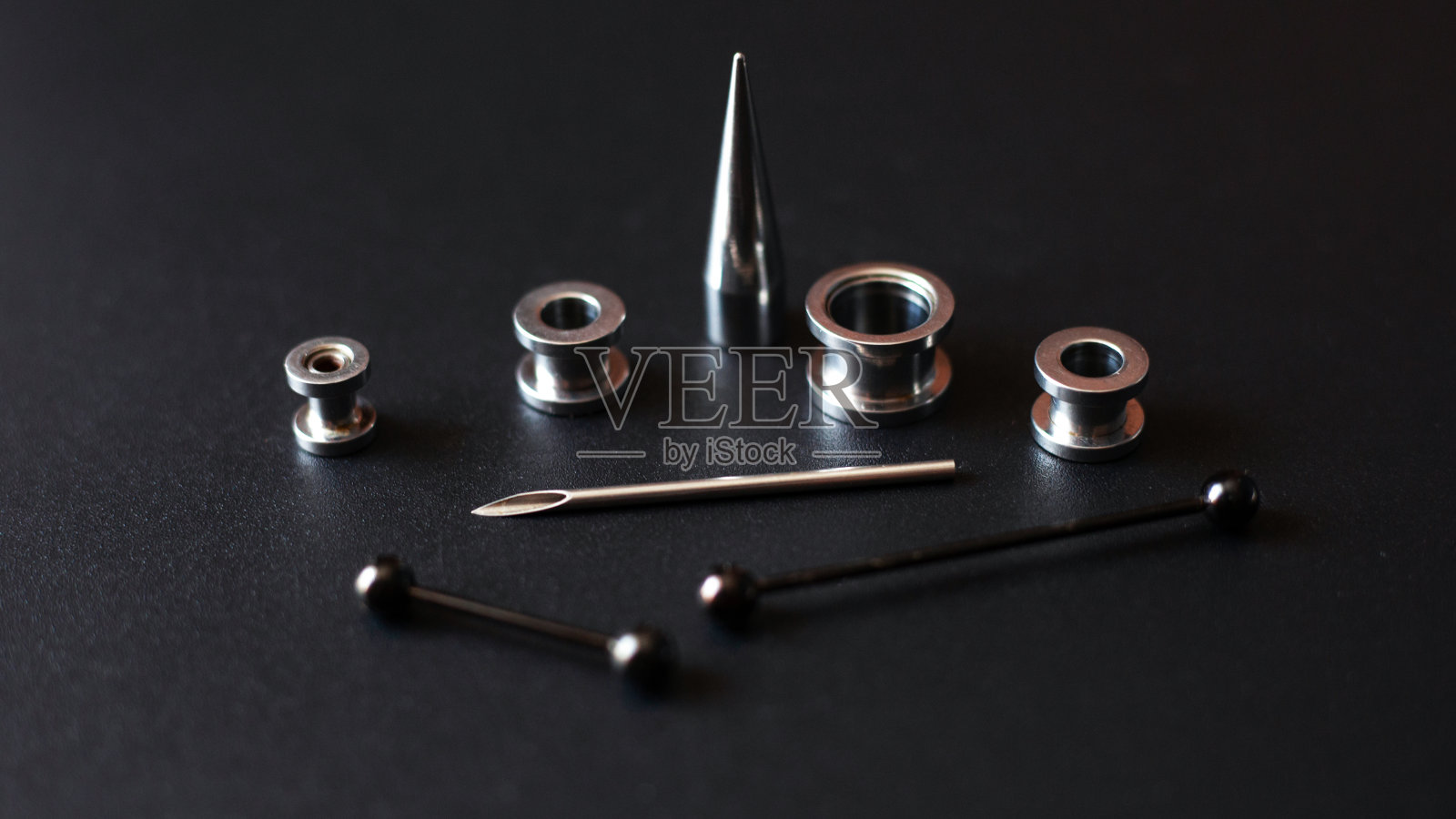 设置为穿洞在黑暗的背景，耳道，隧道和耳环的耳朵和舌头关闭照片摄影图片