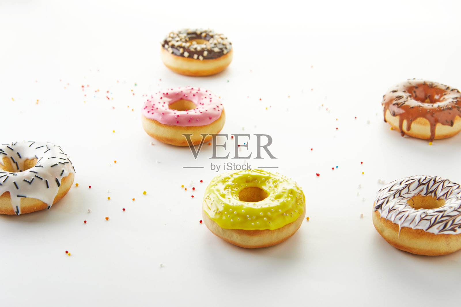 白色背景上带有糖霜和糖屑的彩色甜甜圈照片摄影图片