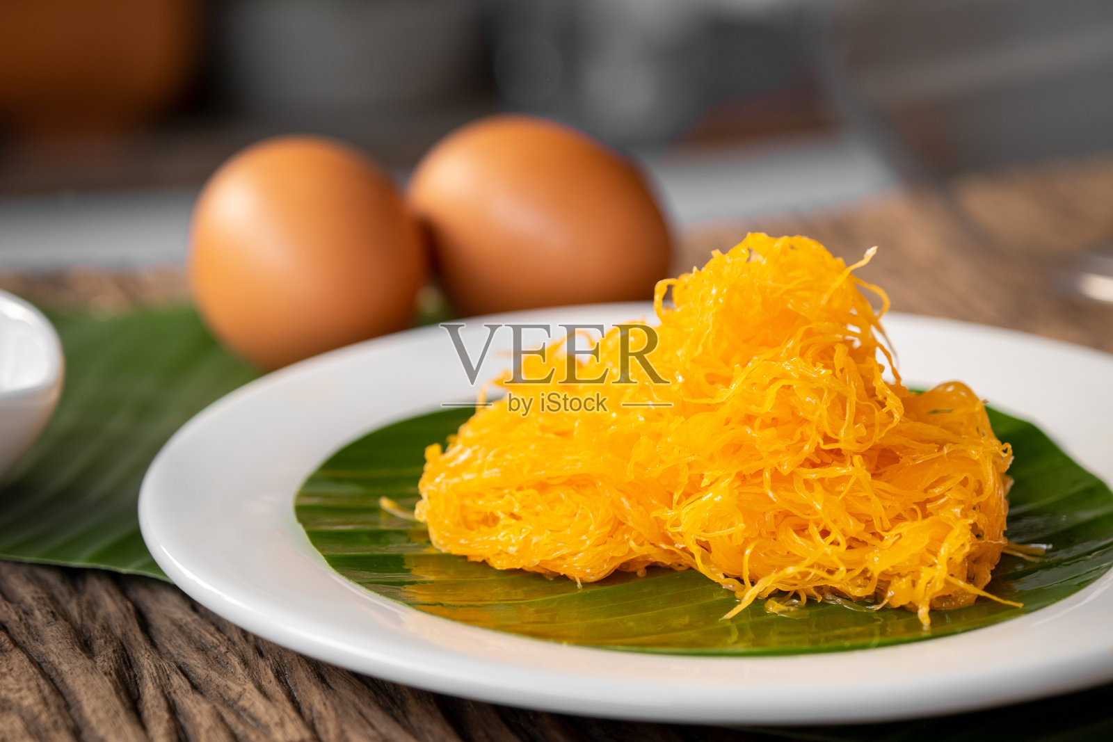 金丝(泰国甜点)放在白色的盘子里，配上香蕉叶。照片摄影图片