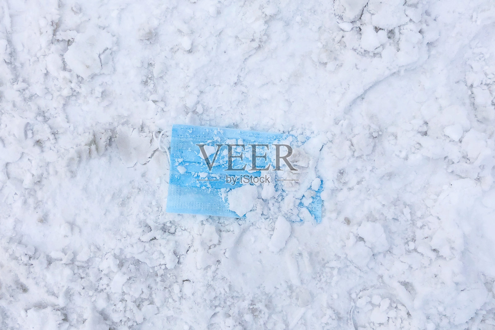 COVID-19和封锁概念。蓝色医用防护口罩上的白雪。俯视图照片摄影图片