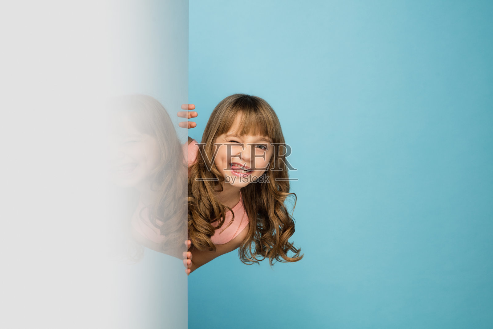快乐的孩子，女孩孤立在蓝色的工作室背景。看起来开心，开朗，真诚。Copyspace。童年，教育，情感概念照片摄影图片