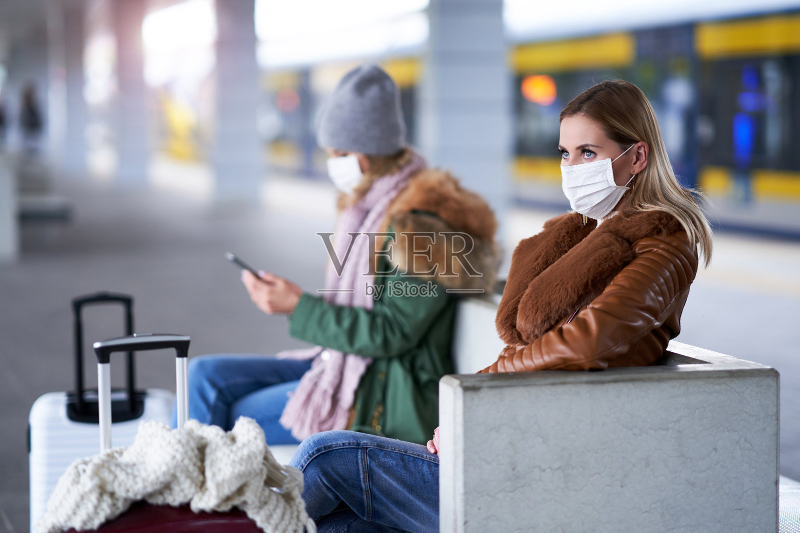 由于新冠肺炎限制，两名妇女在火车站戴口罩照片摄影图片