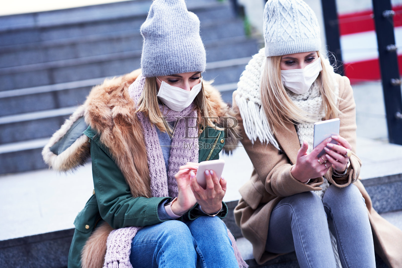 两个女人在城里用智能手机戴着面具照片摄影图片