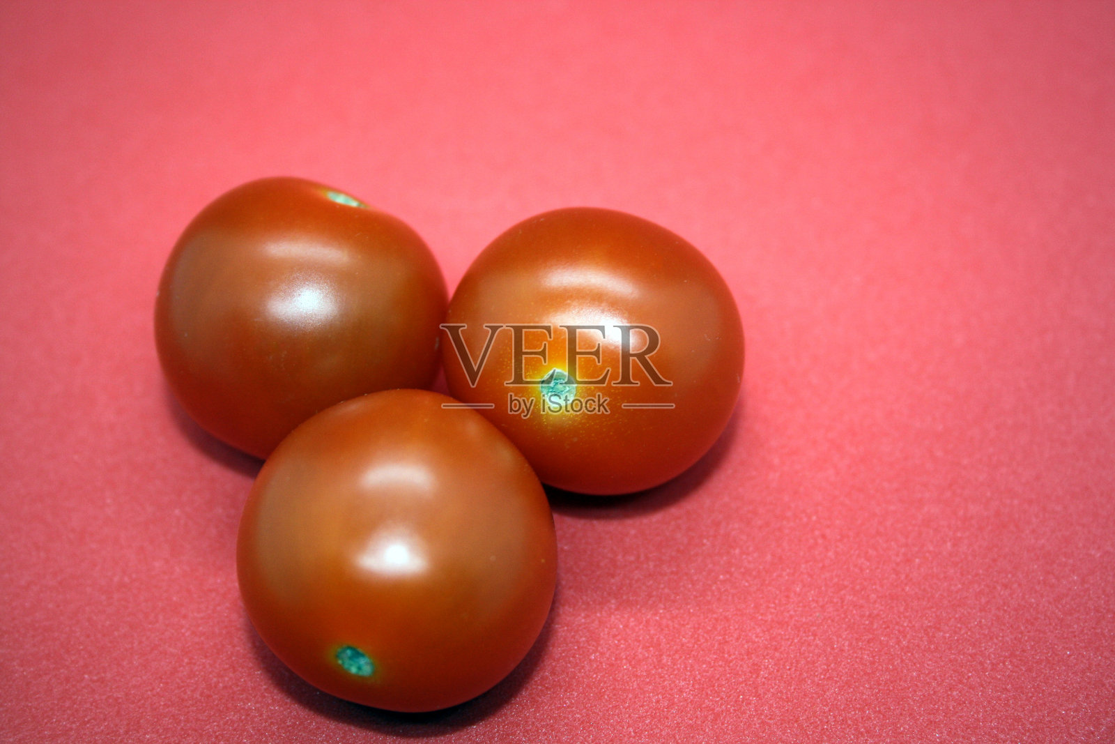 红色背景上孤立的小圣女果。照片摄影图片