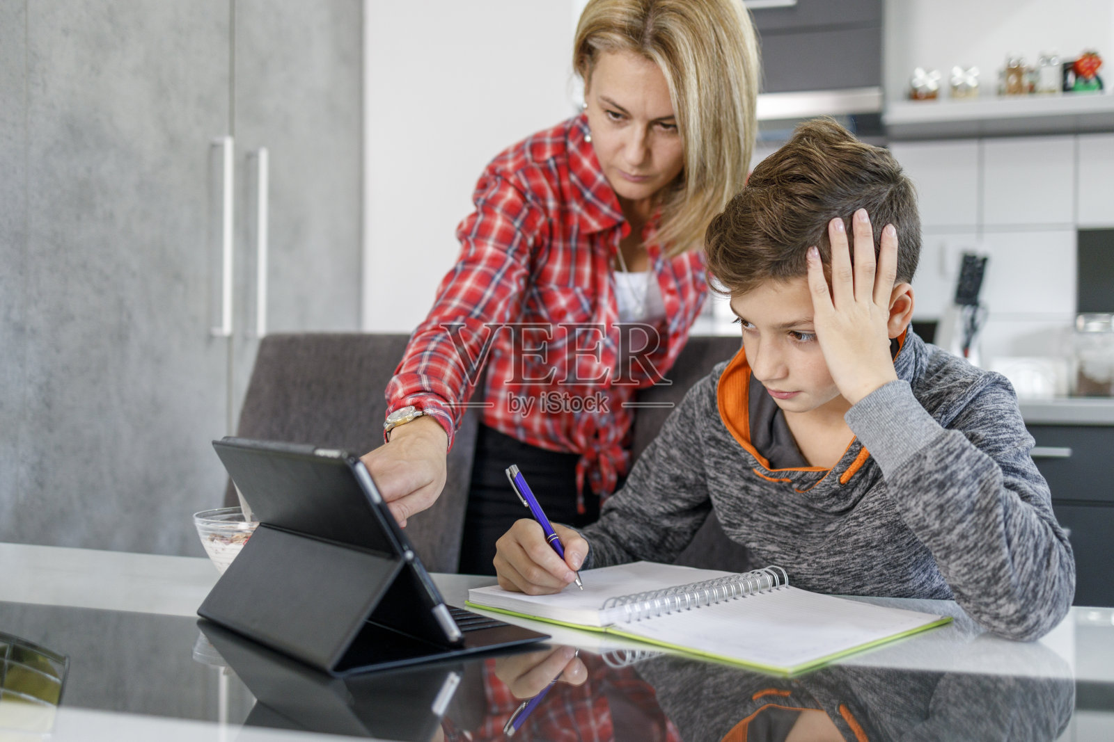 男孩写作业，妈妈通过平板电脑帮助他照片摄影图片