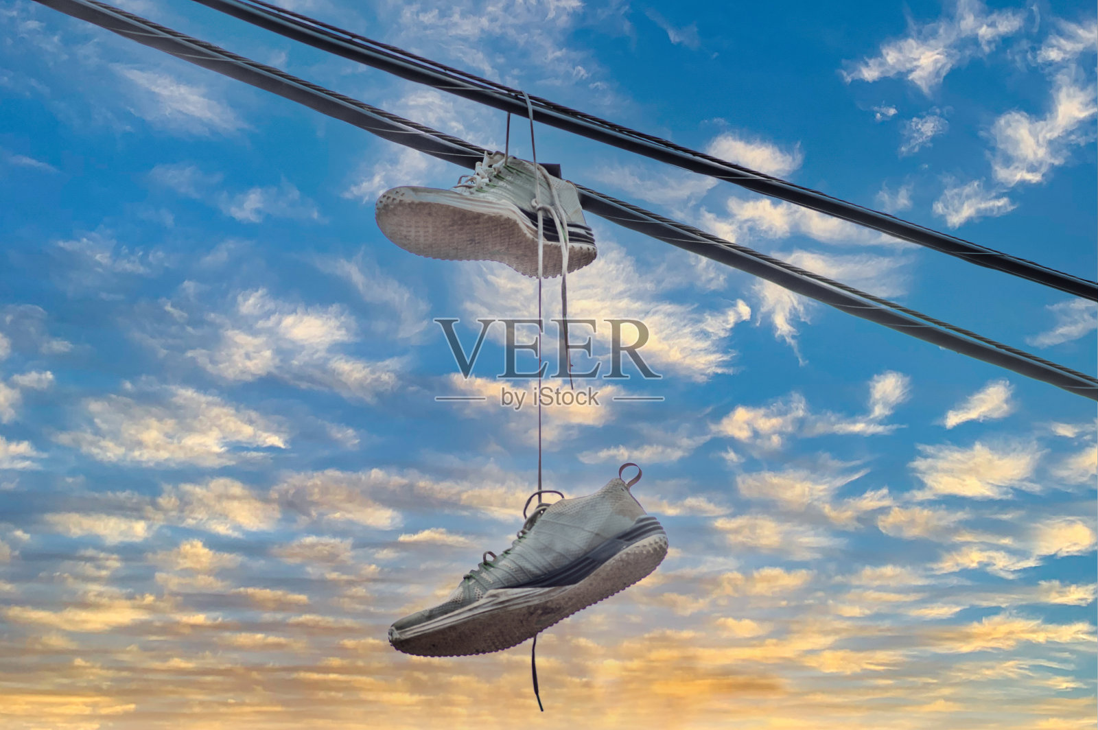 在壮观而多云的天空前，旧球鞋留下了一条皮带照片摄影图片