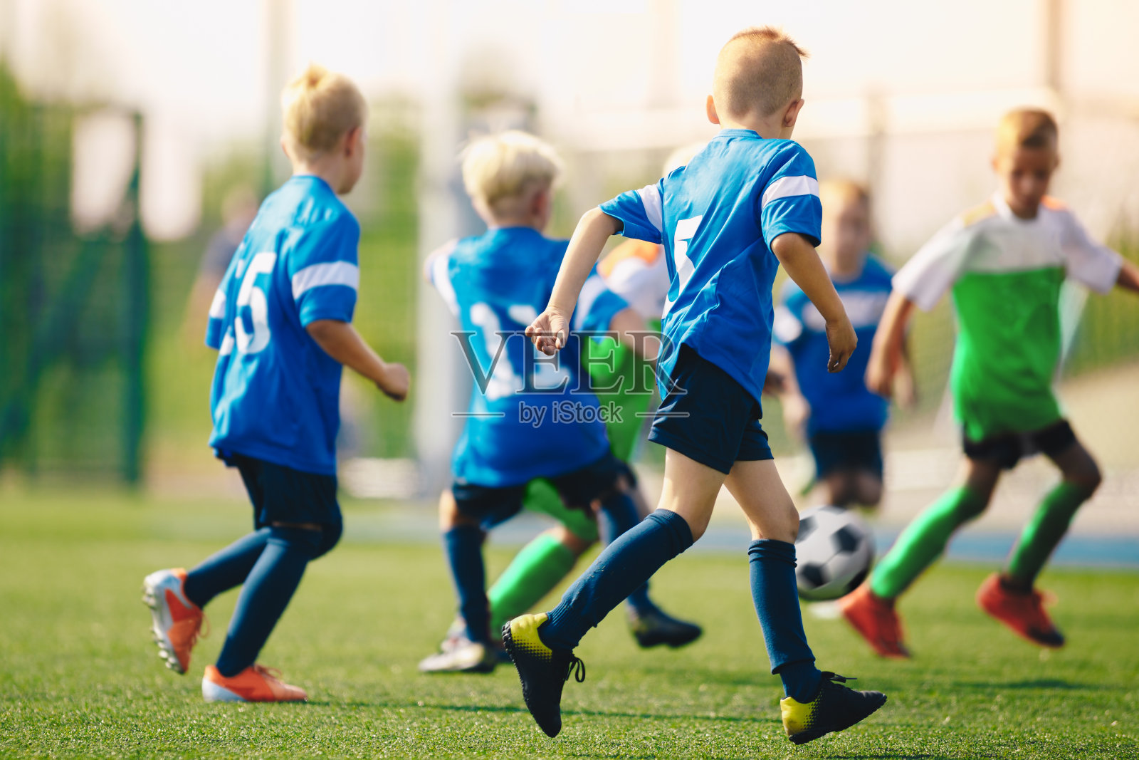 男孩们在学校操场上踢足球。匿名的年轻运动员在一个夏天踢足球照片摄影图片