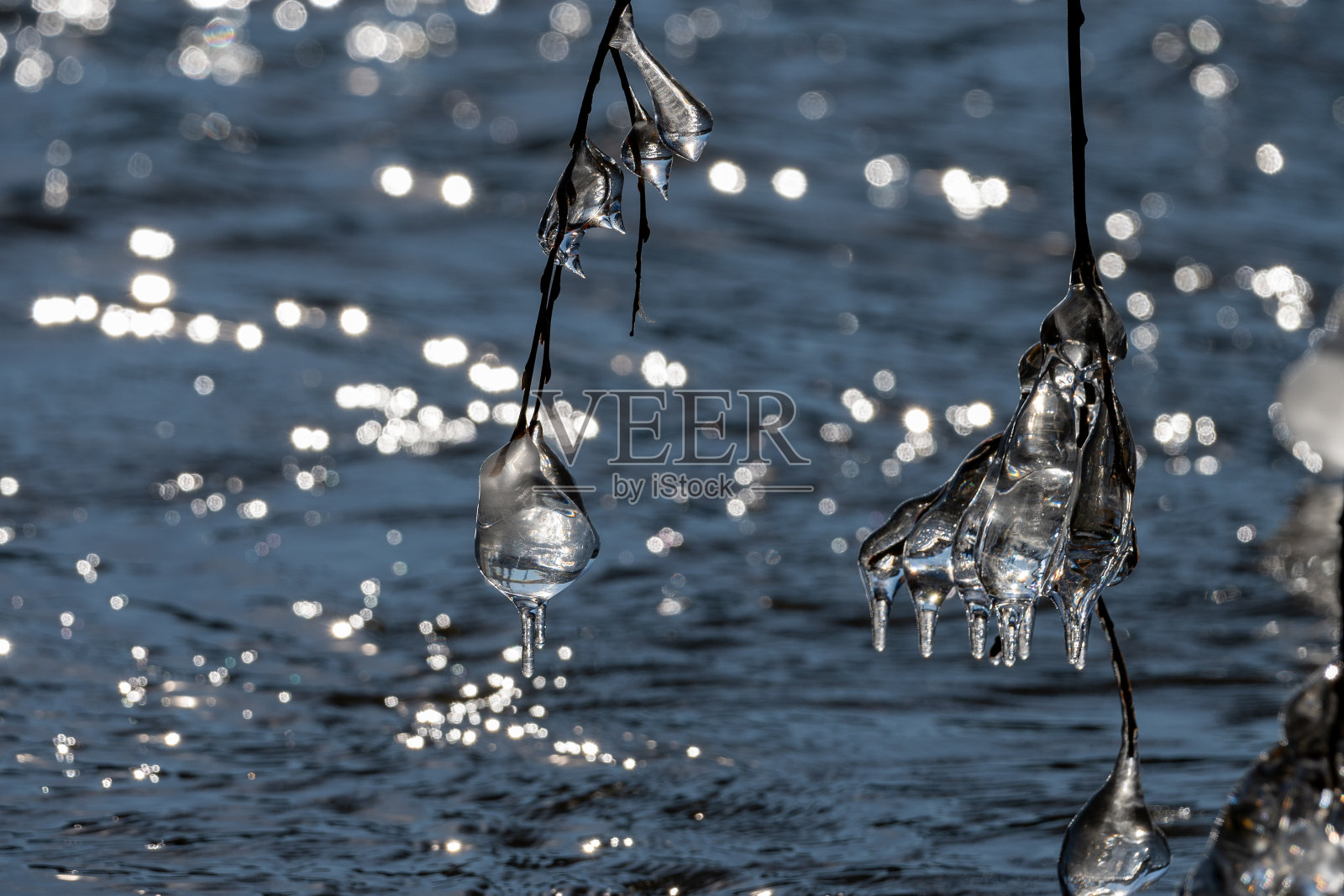 在冬天，光线通过冰柱反射在河流上照片摄影图片