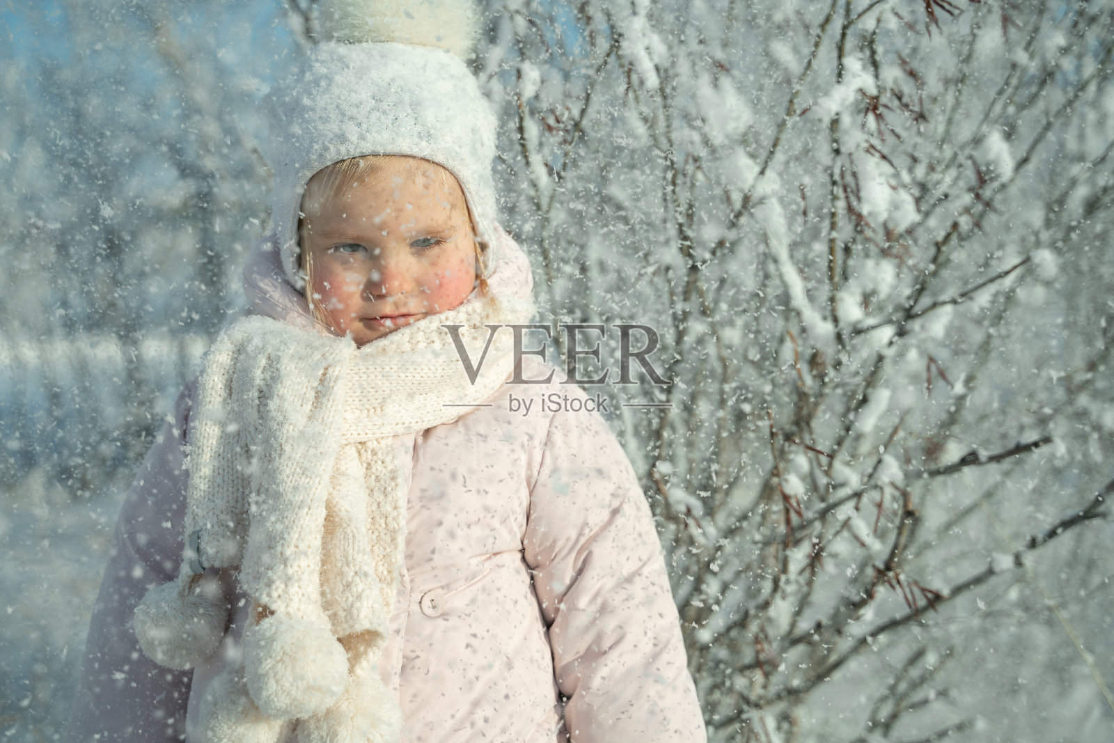 一个孩子戴着温暖的白色帽子和围巾在冬天的森林里玩雪，下雪，冬天的魔法，明亮的情绪，保护皮肤免受霜冻照片摄影图片