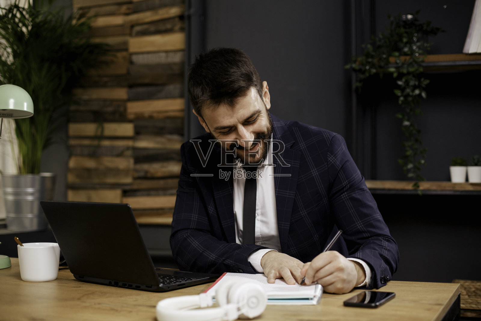 商人一边用笔记本电脑工作一边做笔记照片摄影图片