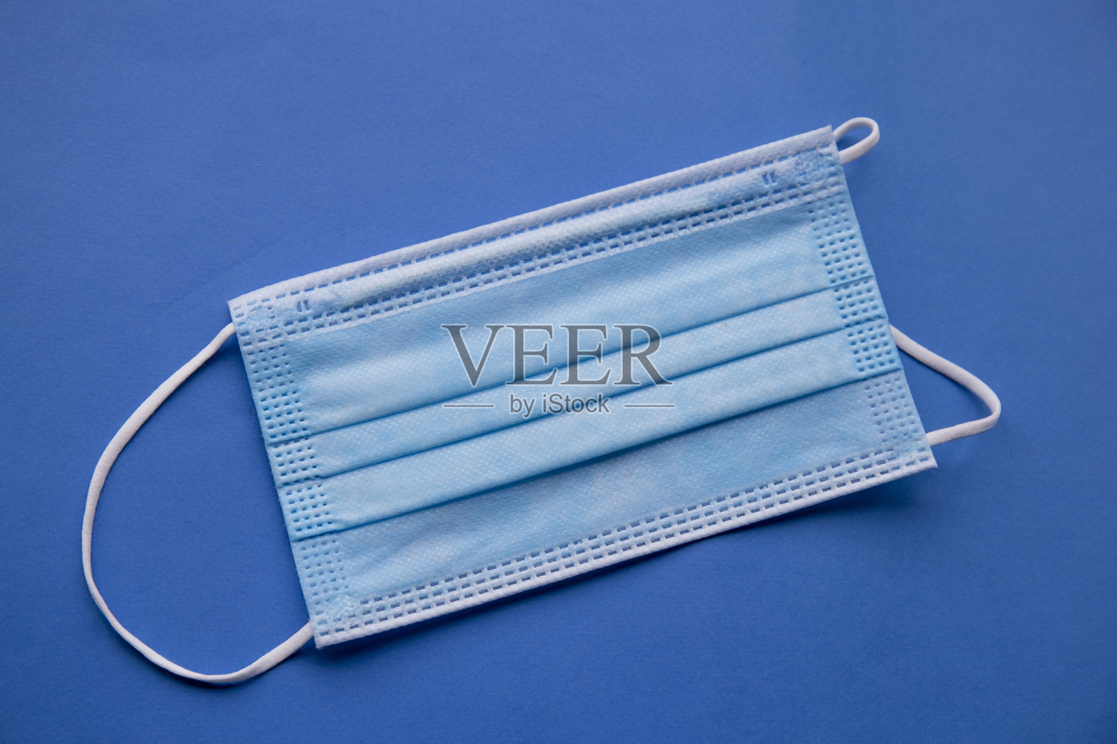 几个医用口罩平铺在蓝色的表面上照片摄影图片