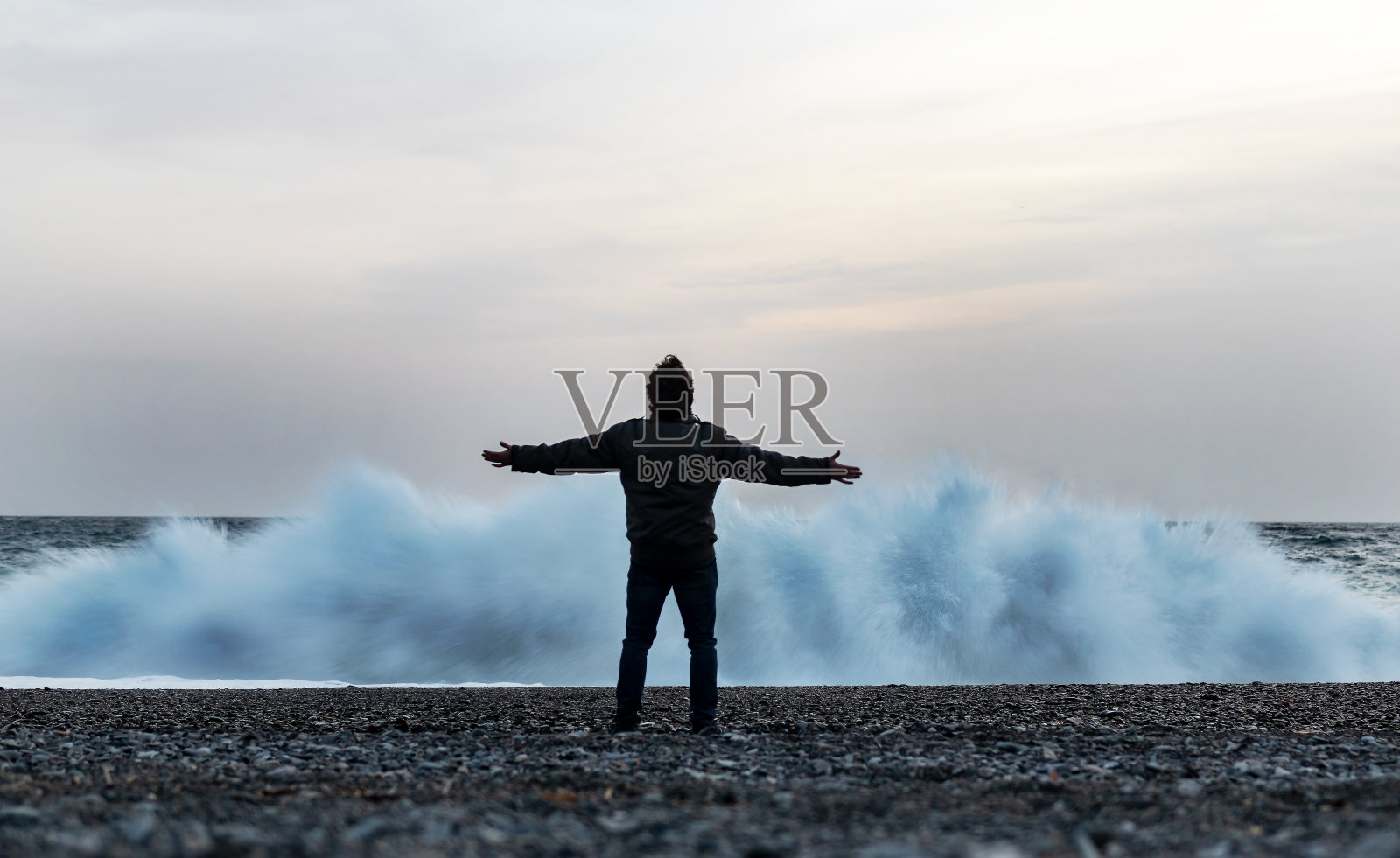 一个男人在海滩上的大浪前挑战大海照片摄影图片