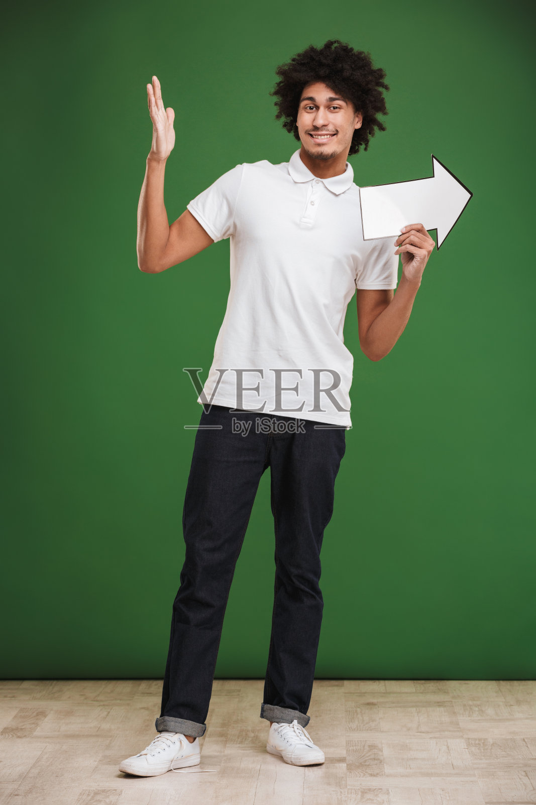 快乐的年轻非洲卷毛男人拿着箭头指向。照片摄影图片