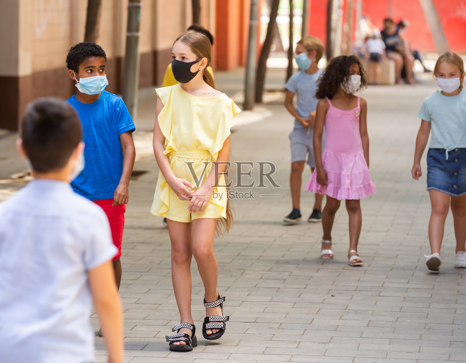 一群戴着医用防护口罩的孩子在晴朗的天气里走在街上照片摄影图片