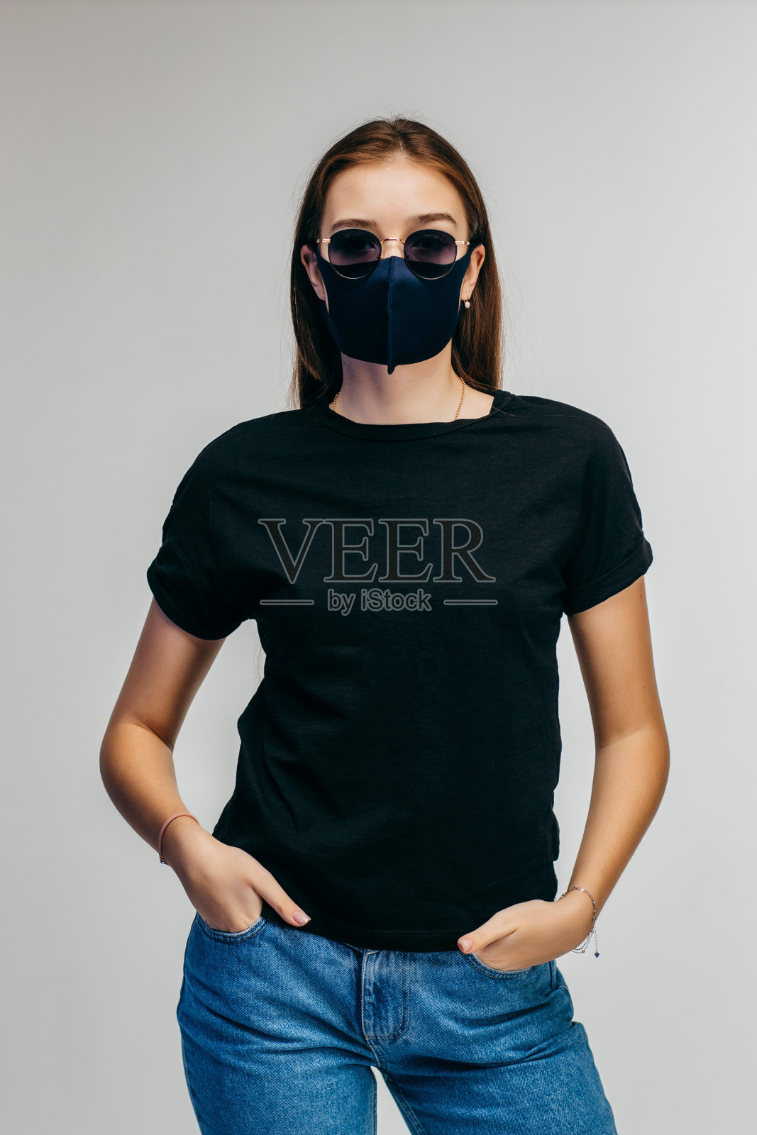 时尚的女孩戴着眼镜和面具，穿着黑色t恤，在工作室的灰色背景照片摄影图片