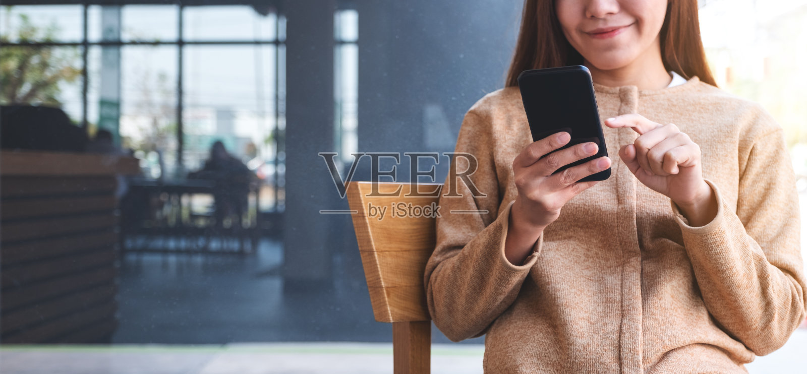 一个美丽的年轻亚洲女人拿着并使用手机照片摄影图片