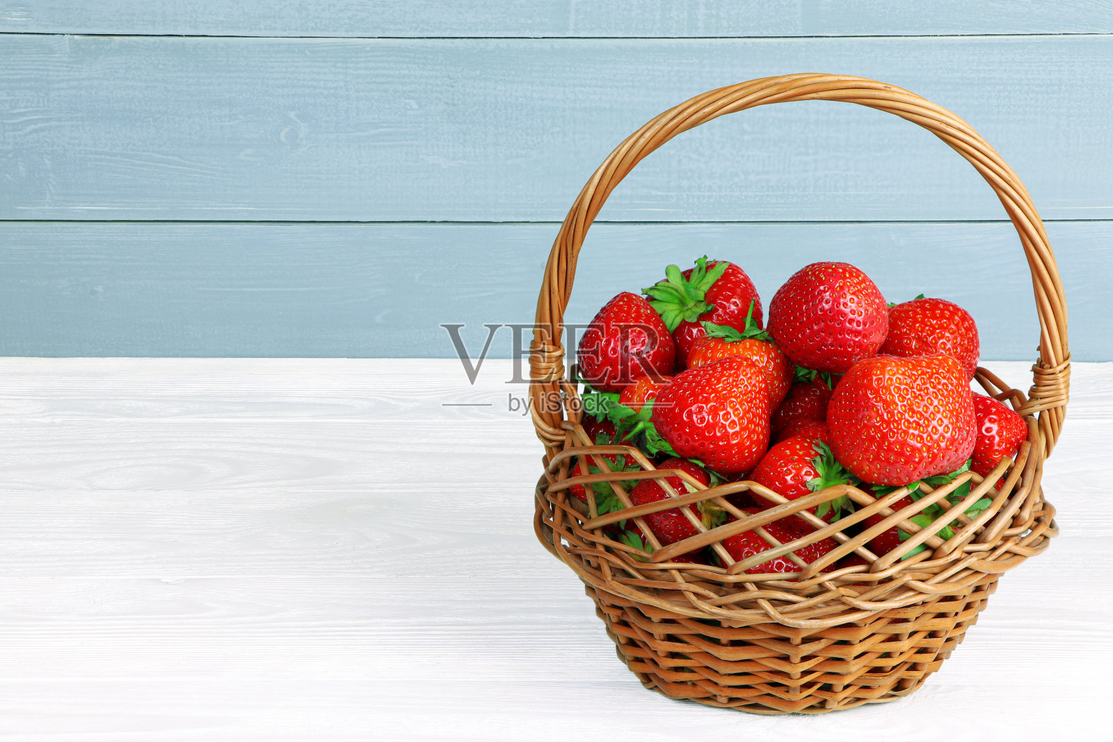 白木桌上的木篮子里放着新鲜的草莓。健康食品。有机草莓照片摄影图片