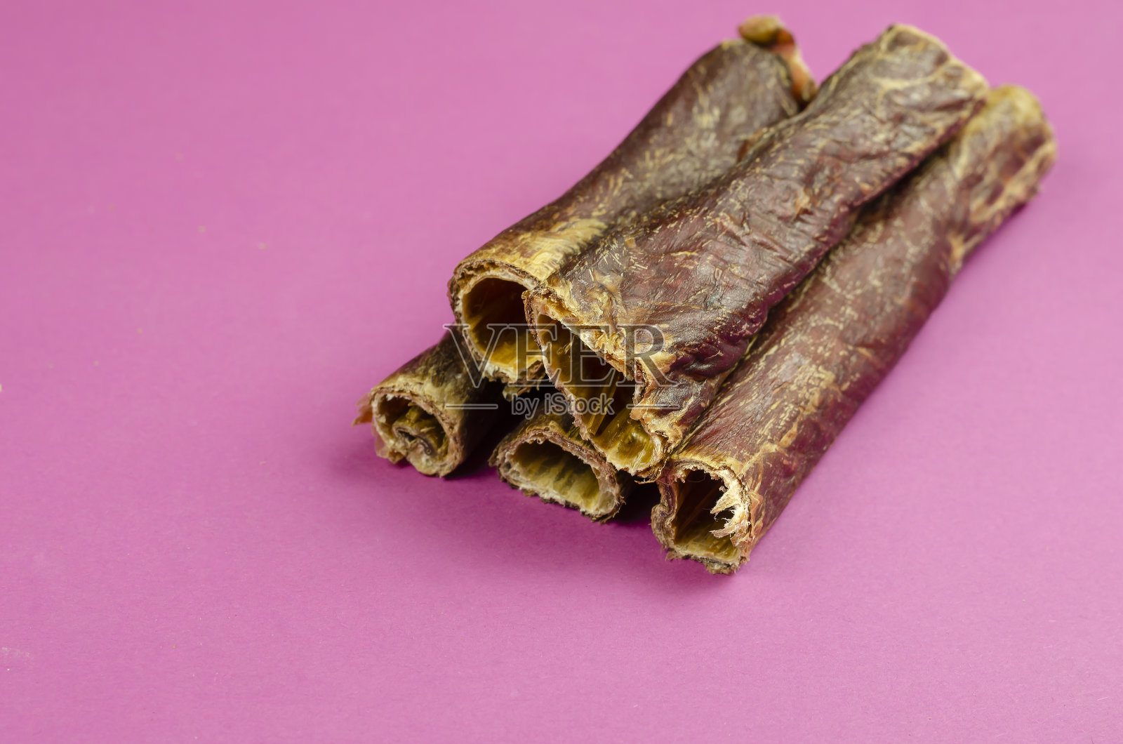 纯天然健康的狗粮100%优质。干牛肉食道，水牛内脏在粉红色的背景。照片摄影图片