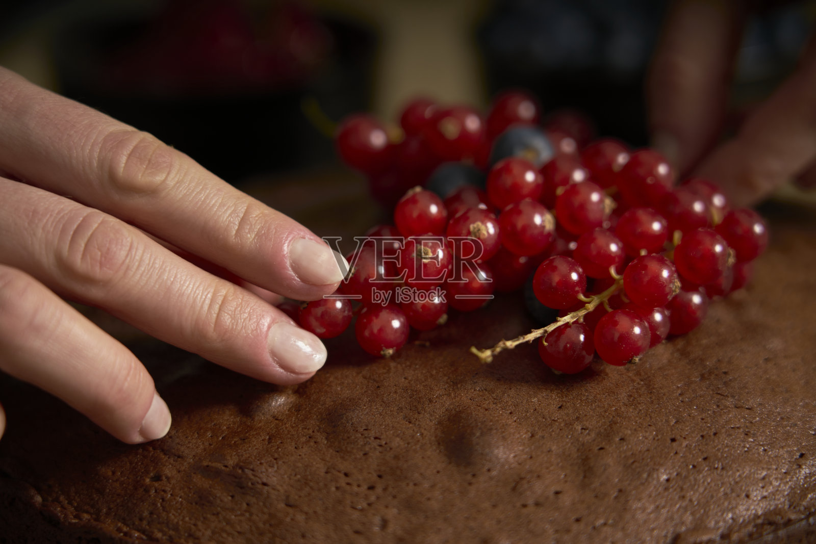 热爱烹饪的女士装饰手工巧克力蛋糕。照片摄影图片