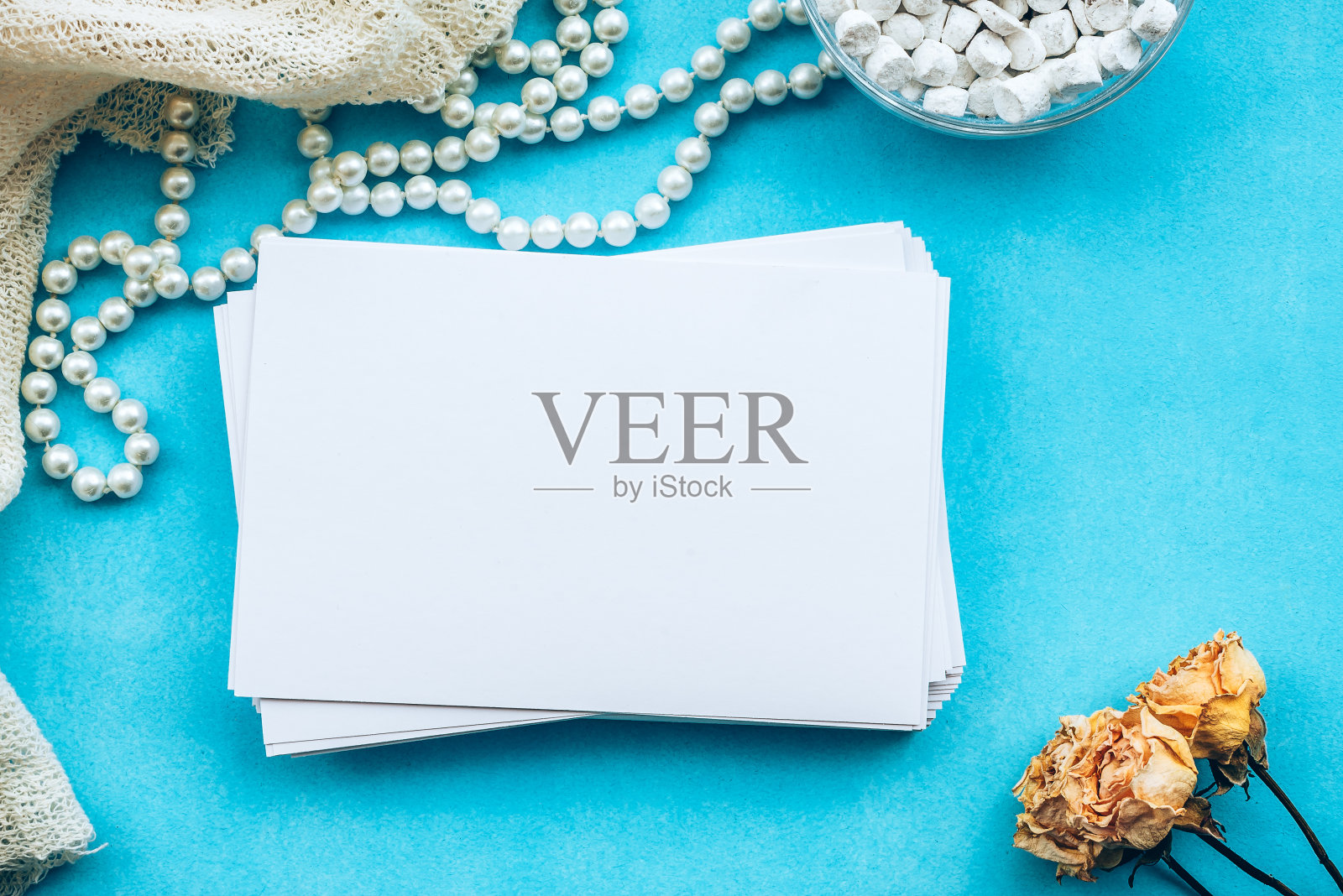 白色空白卡片和蓝色背景的黄色玫瑰。一张温柔浪漫的空白明信片。婚礼请帖和复印空间，俯视图。照片摄影图片