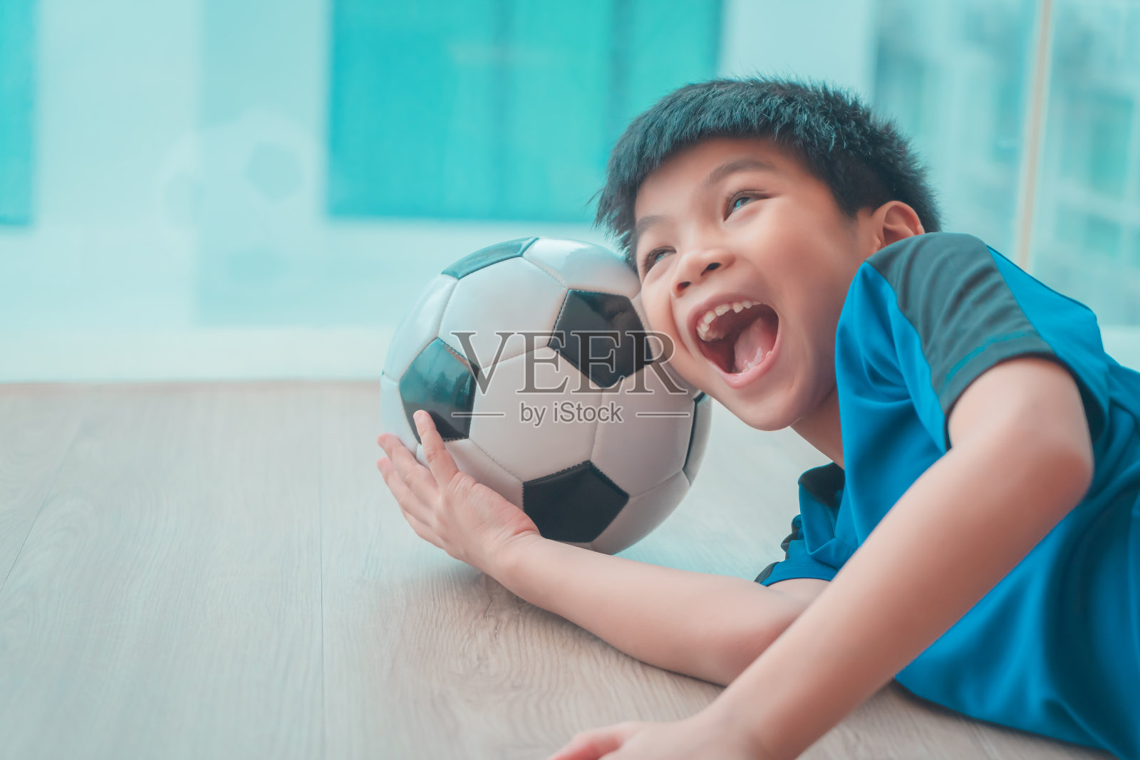 有趣的年轻亚洲足球运动员的孩子睡在一个足球在他的头。照片摄影图片