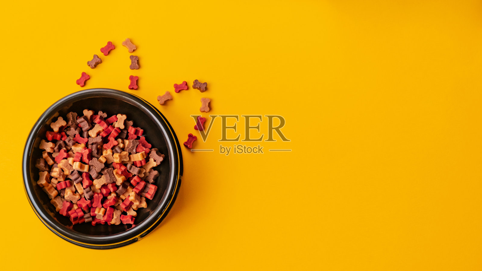 狗干脆骨头的形式是在黑色狗板。脆脆的天然小狗零食和营养。文本空间。芥末颜色。横幅照片摄影图片