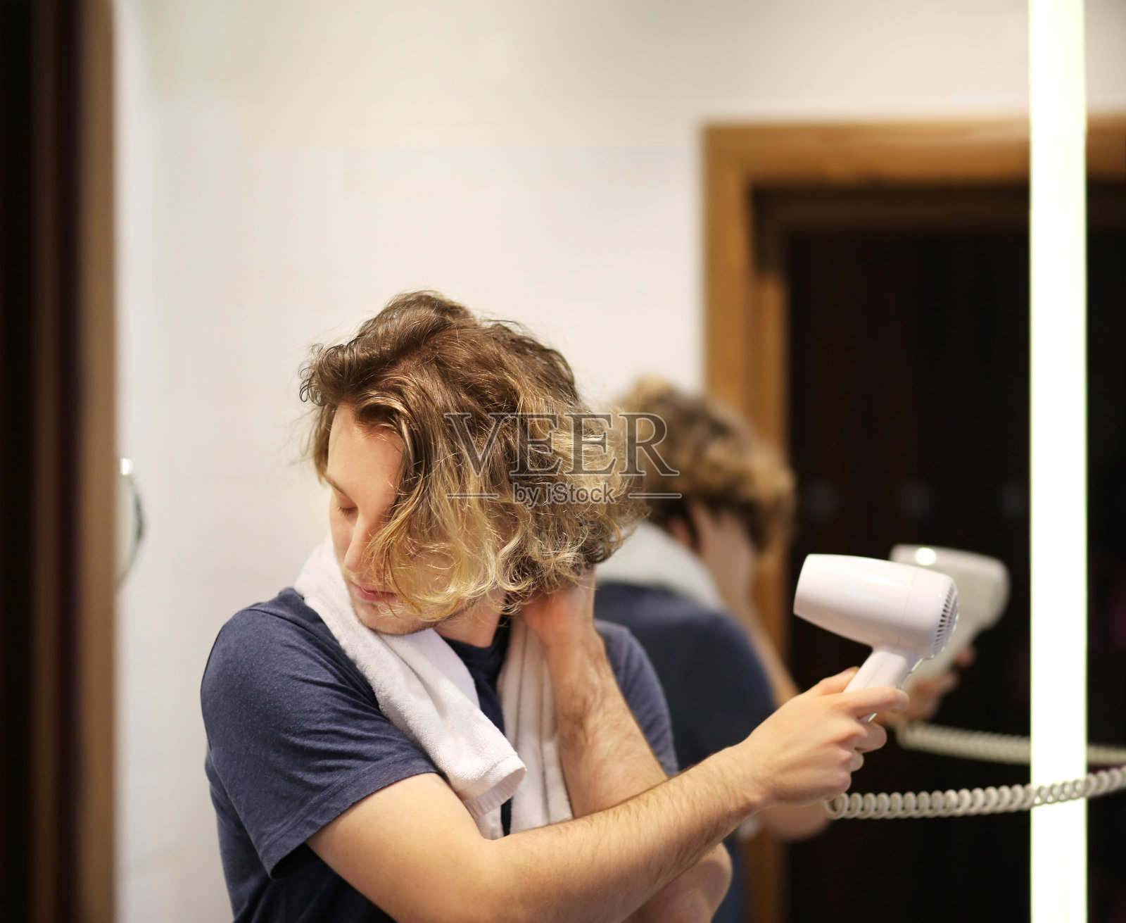 一个男人在浴室里用吹风机吹头发照片摄影图片