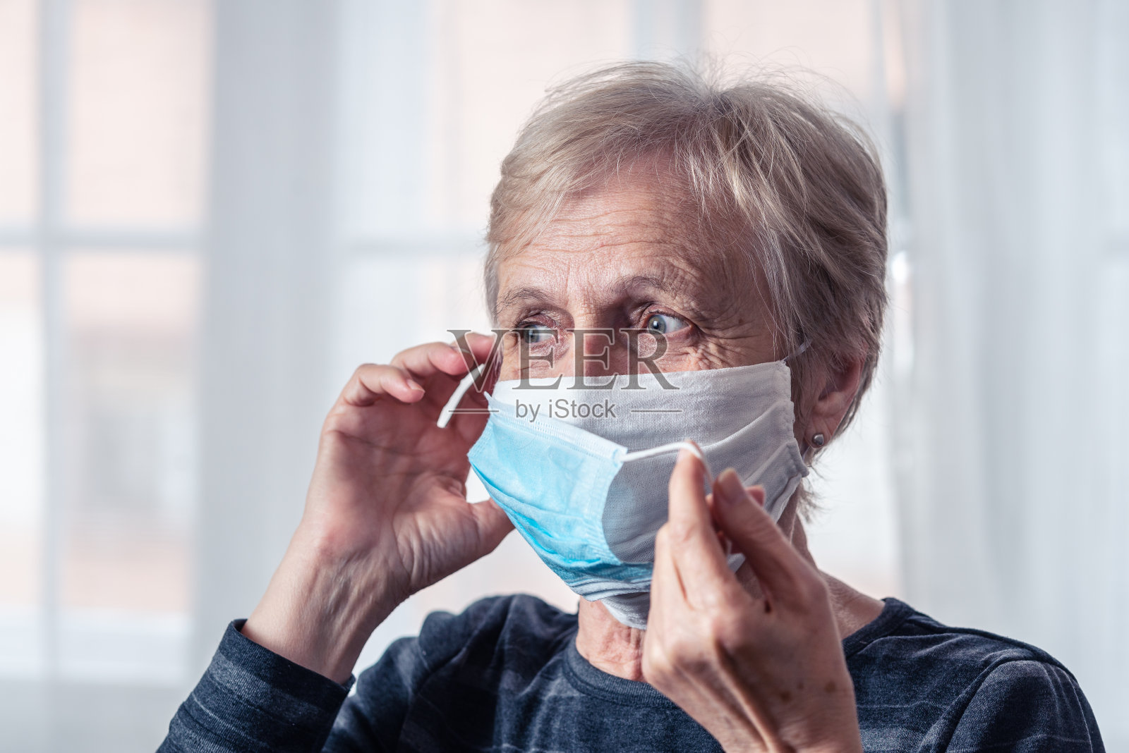 老妇人戴着两个口罩预防Covid-19照片摄影图片