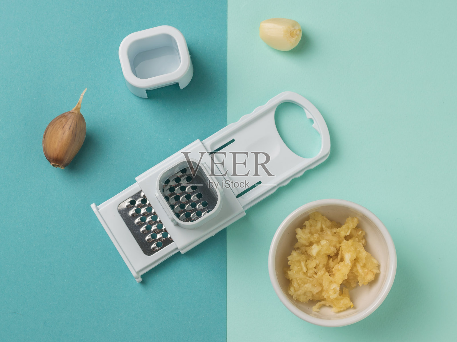 磨碎器和大蒜在浅蓝色和深蓝色的背景。照片摄影图片