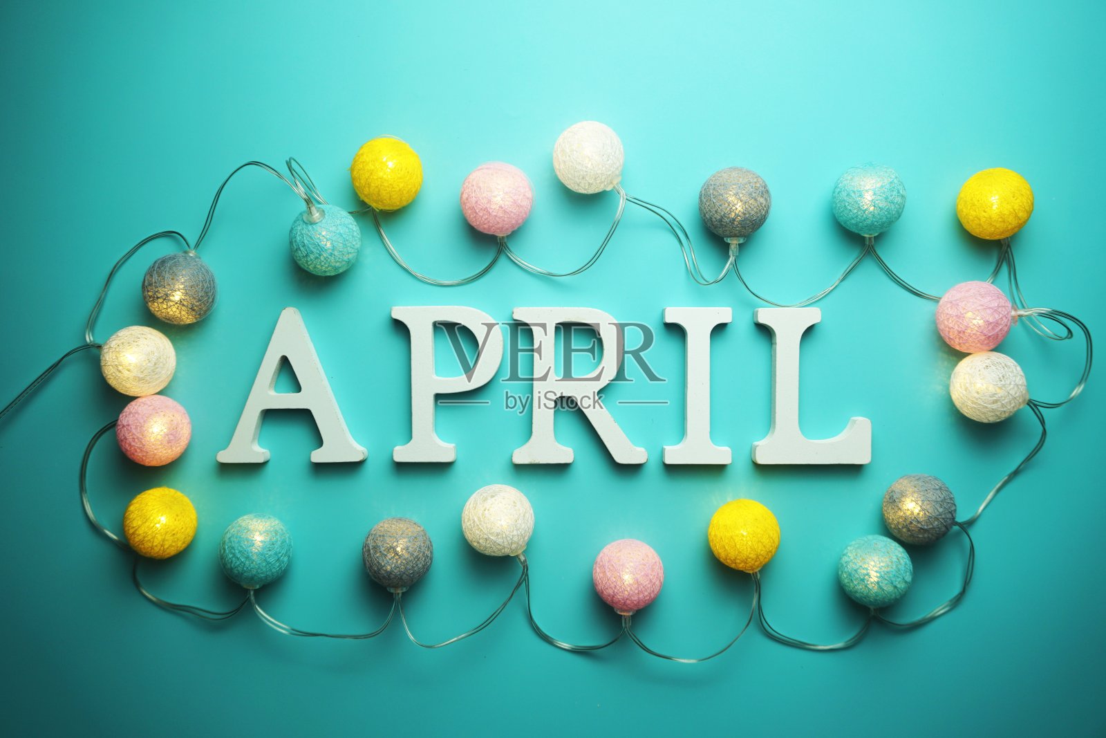 四月字母与棉球LED装饰在蓝色的背景照片摄影图片